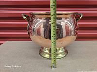 Front view of copper pot with tape measure showing height