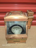 Front view of copper binnacle showing compass through glass and side oil lamp housing