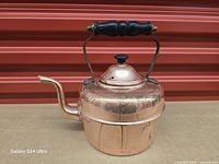 Full view right side of copper kettle showing handle, spout and seam
