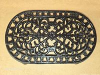 Top view of black cast iron oval trivet showing full openwork pattern
