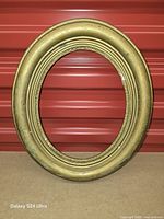 Front view of entire oval frame showing overall form and gilt finish