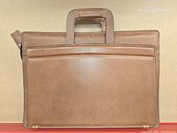 Rear view of brown leather briefcase showing exterior slip pocket and integrated handles