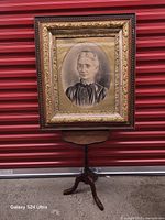 Full view of framed portrait on stand against red background