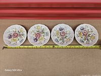Four Johnson Bros Sheraton plates aligned with tape measure