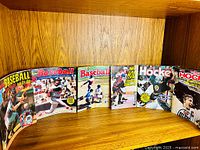 Six sticker albums displayed open on shelf