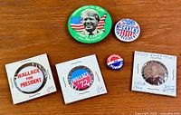 All six presidential buttons laid out on wood surface