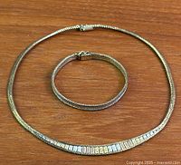 Bracelet and necklace laid flat to show matching design and overall condition