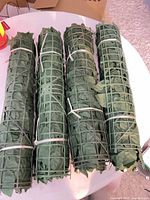 Four rolled artificial leaf privacy screens on table