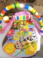 Play gym assembled showing mat, arches, pink piano panel, bag of link rings