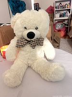 Front view of cream plush teddy bear seated showing full body and bowtie