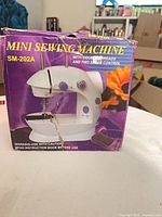 Front of box showing image of SM-202A mini sewing machine
