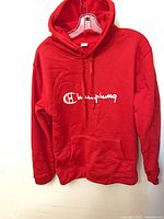 Front view showing red pullover hoodie with white script logo and kangaroo pocket