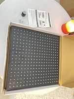 Front of square matte black shower head with nozzle grid in open box