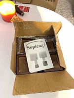 Open box showing four square wooden caps wrapped in bubble wrap and Sopicoz leaflet