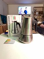 Stainless steel moka pot beside its box and leaflet