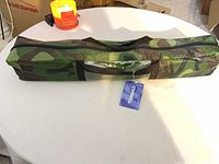 Camo tent in carry bag with TOMSHOO tag on table