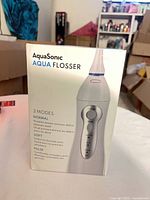 Front of retail box showing AquaSonic Aqua Flosser image and branding