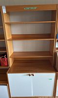 Full view of bookcase with three shelves and lower white two-door cabinet