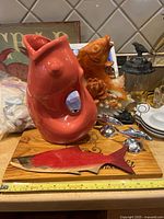 Group view showing ceramic fish vase, fish bookend, wooden fish board, silver fish holders, frog figurine