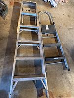 Both ladders laid flat on concrete floor