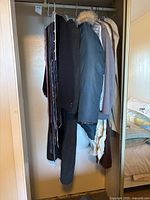 Closet view of coats, pants, shirts and neckties on hangers