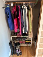 Full closet view showing hanging outerwear and footwear on shelf and floor