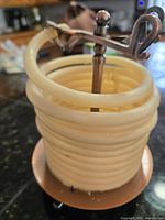 Full view of coiled beeswax candle on copper stand showing form and materials