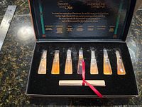 Open box showing seven vials and scroll in velvet insert
