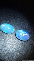 Pair of oval crystal opals on black background