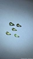 Five pear-cut yellow-green tanzanite gemstones on a neutral background