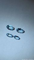 Four light blue oval faceted stones displayed on neutral background