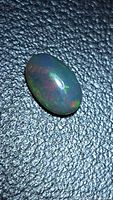 Top view of oval black opal displaying red and green play-of-color