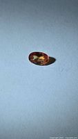 Front view of oval orange-red sapphire on neutral background