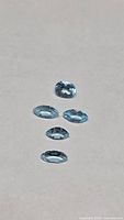 Five sky blue topaz gemstones on neutral background
