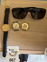Three watches and sunglasses displayed on tabletop