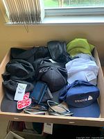 Drawer view with assorted caps, wallets, sunglasses, patches and gloves