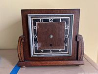 Front view of wooden mantel clock showing square dial without hands
