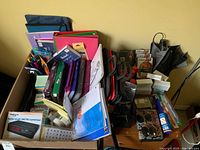 Overview of two boxes filled with binders, folders, pens and assorted office items alongside toiletries and bags