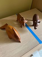 All three wooden animal statues on tabletop showing relative sizes