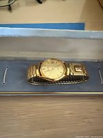 Watch in open blue box displaying bracelet and dial