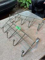 Two chrome metal over-door hangers with six hooks each on tabletop