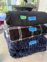 Stacked view of the three folded throw blankets showing colors, textures and size labels