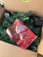 Garland coiled in shipping box with Santa insert and battery case visible