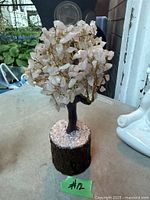 Front view of rose quartz tree showing crystal leaves, trunk, and wooden base