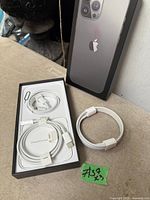 Cable coiled in original iPhone tray with SIM-eject pin and separate view of cable