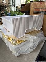 Stacked ribbed plastic panels and grid floors from playpen kit beside original box