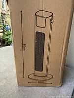 Front of sealed box showing outline drawing of tower heater with 60 cm height and 23 cm base width.