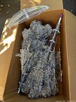 Tree sections in shipping box showing silver tinsel branches and purple-tipped trunk
