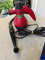 Full view of red Comforday handheld steam cleaner with hose attachment and cord