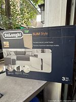 Front of retail box showing DeLonghi Slim Style portable electric panel heater imagery and branding